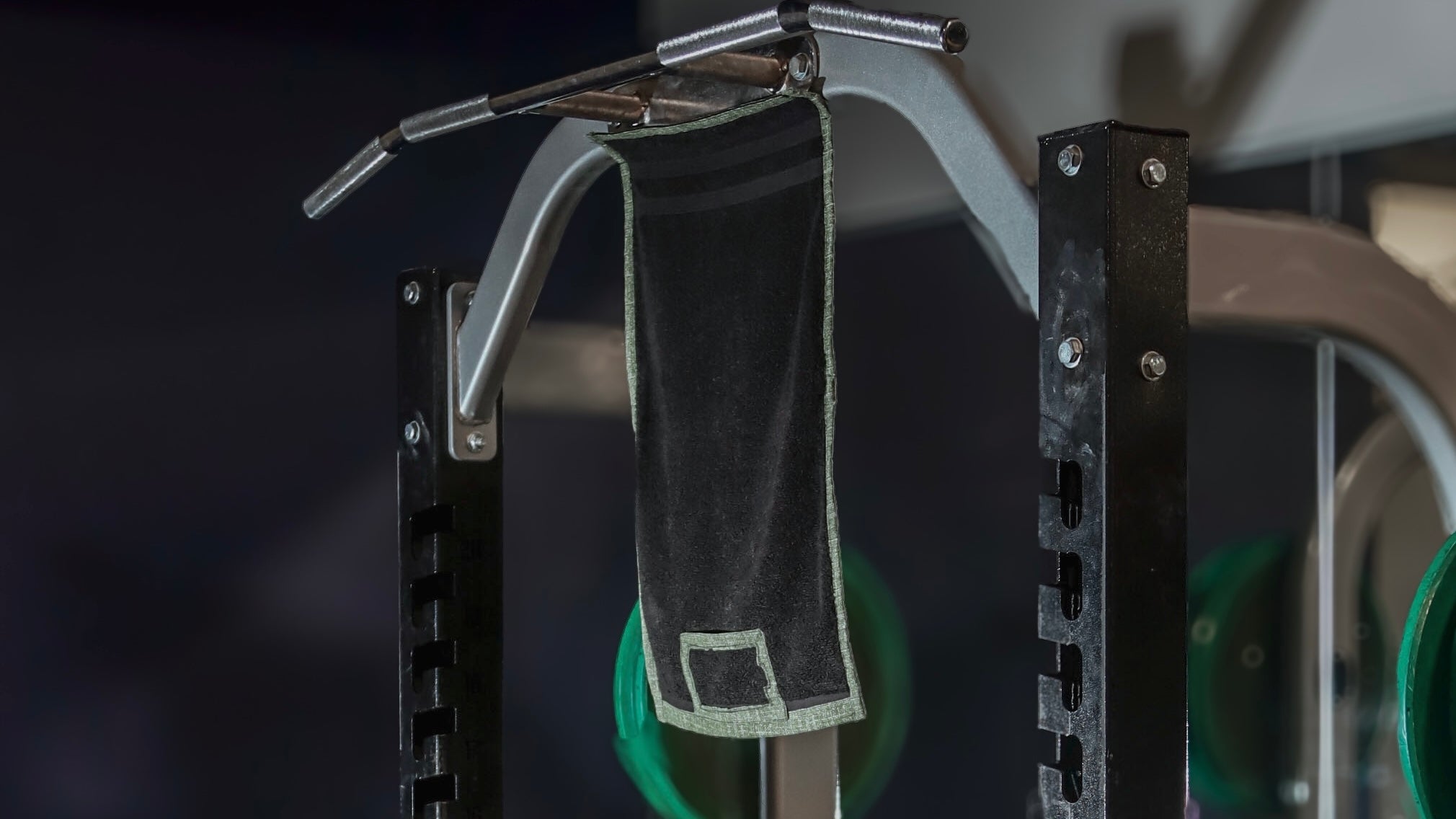 Media towel hanging from squat rack for optimal height for best lifting form gym setup.