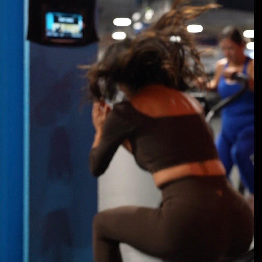 Person exercising on a box jump in a gym setting with media towel hanging in front.