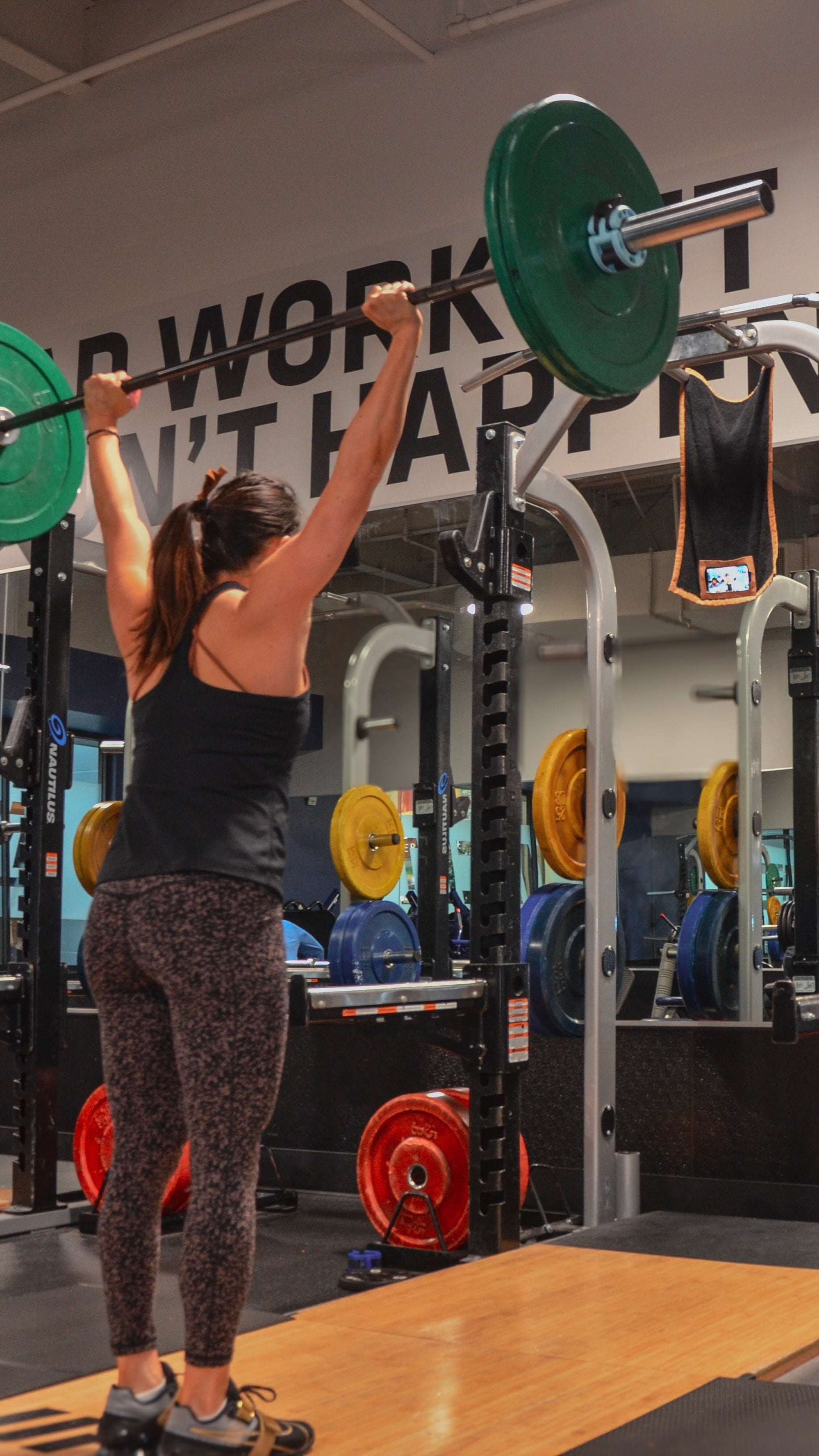 Woman lifting a barbell in a gym with perfect form using Media Towel