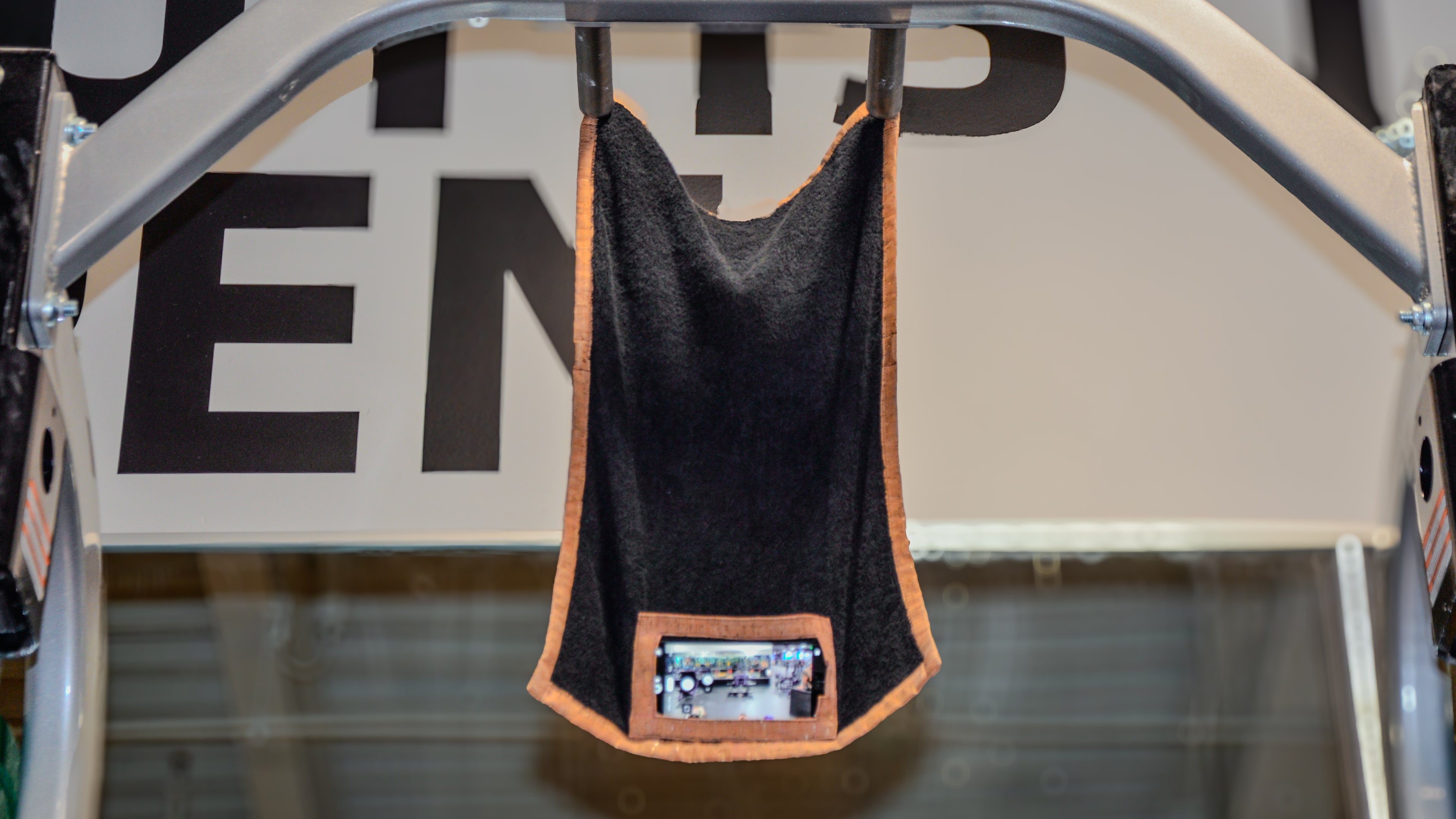 Black media towel with orange trim with magnets hanging on a metal rack.