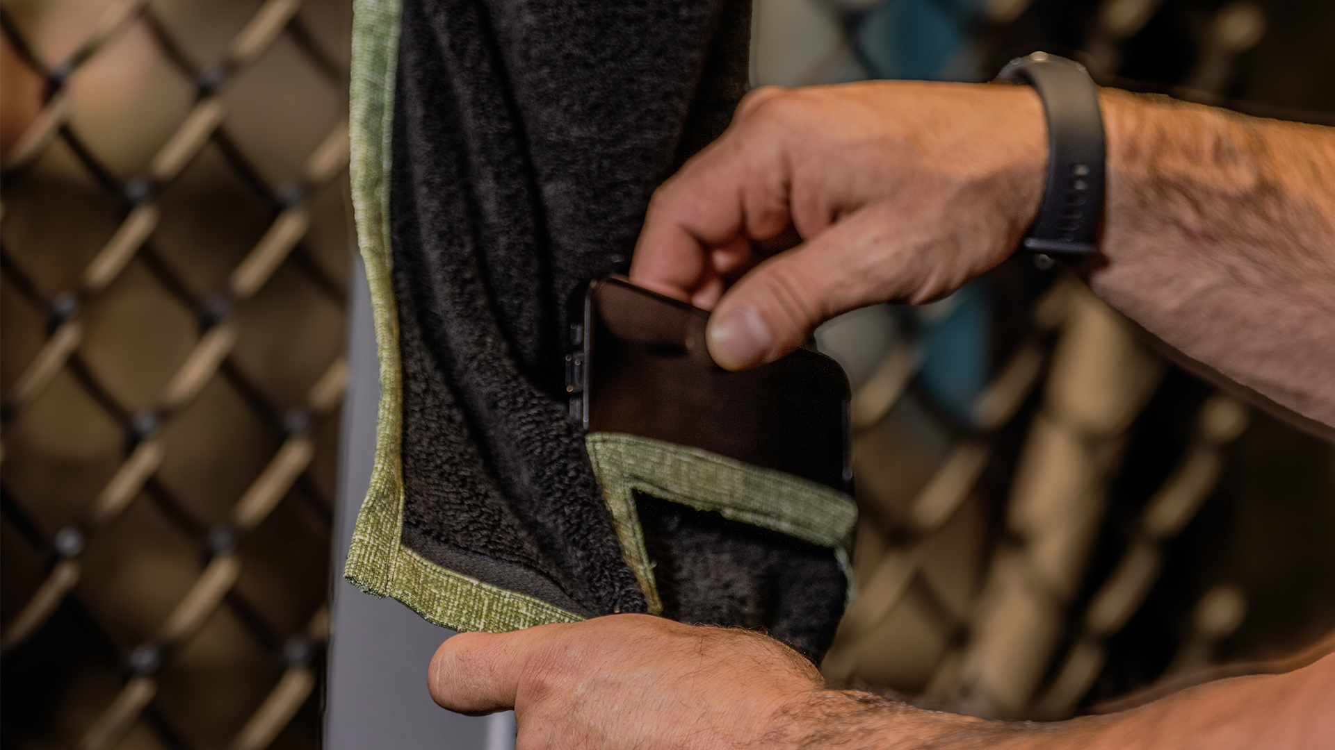 Person putting phone in a green and black media towel for secure recording.