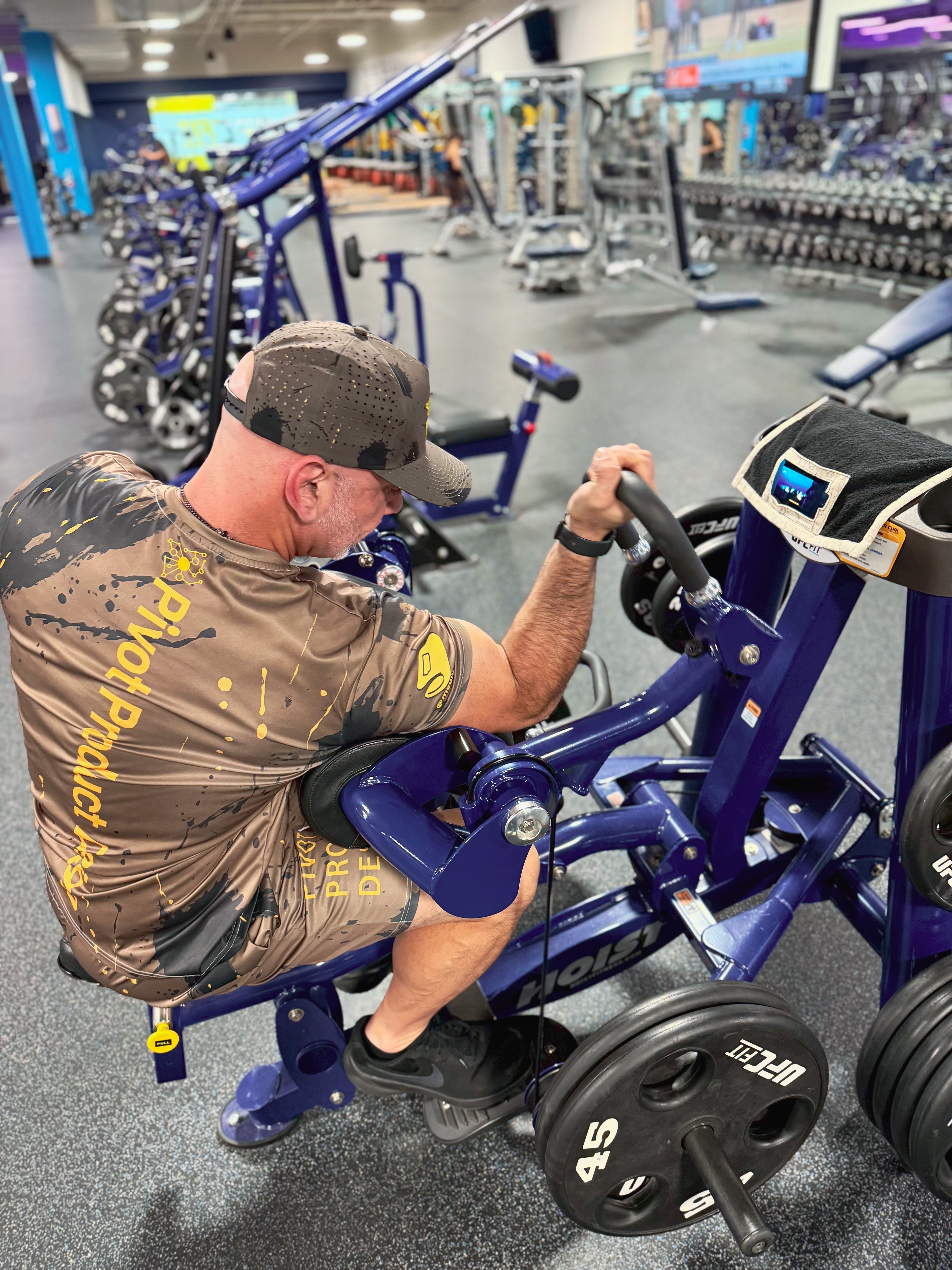 Man exercising bicep curls using Media Towel to Watch fitness content in gym.