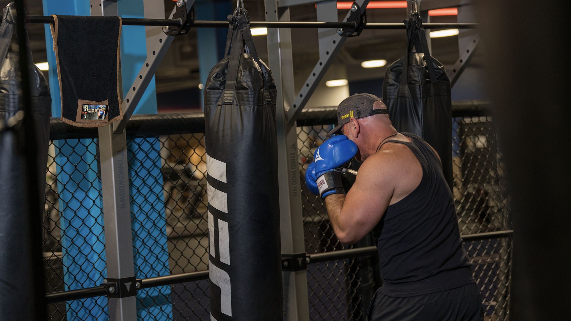 Person boxing and training with a punching bag in a gym using media towel.