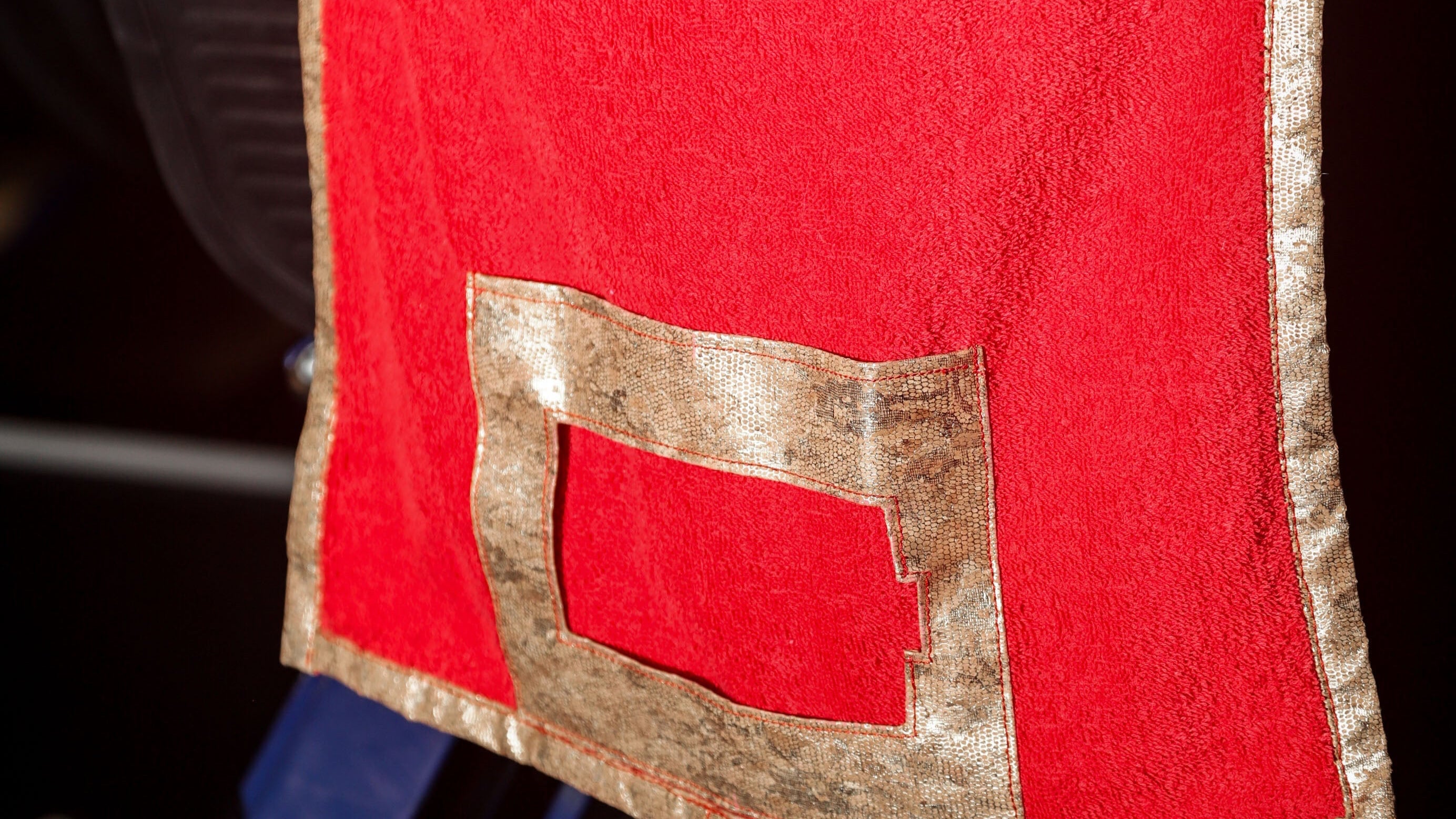 Red fabric with gold trim on a dark background