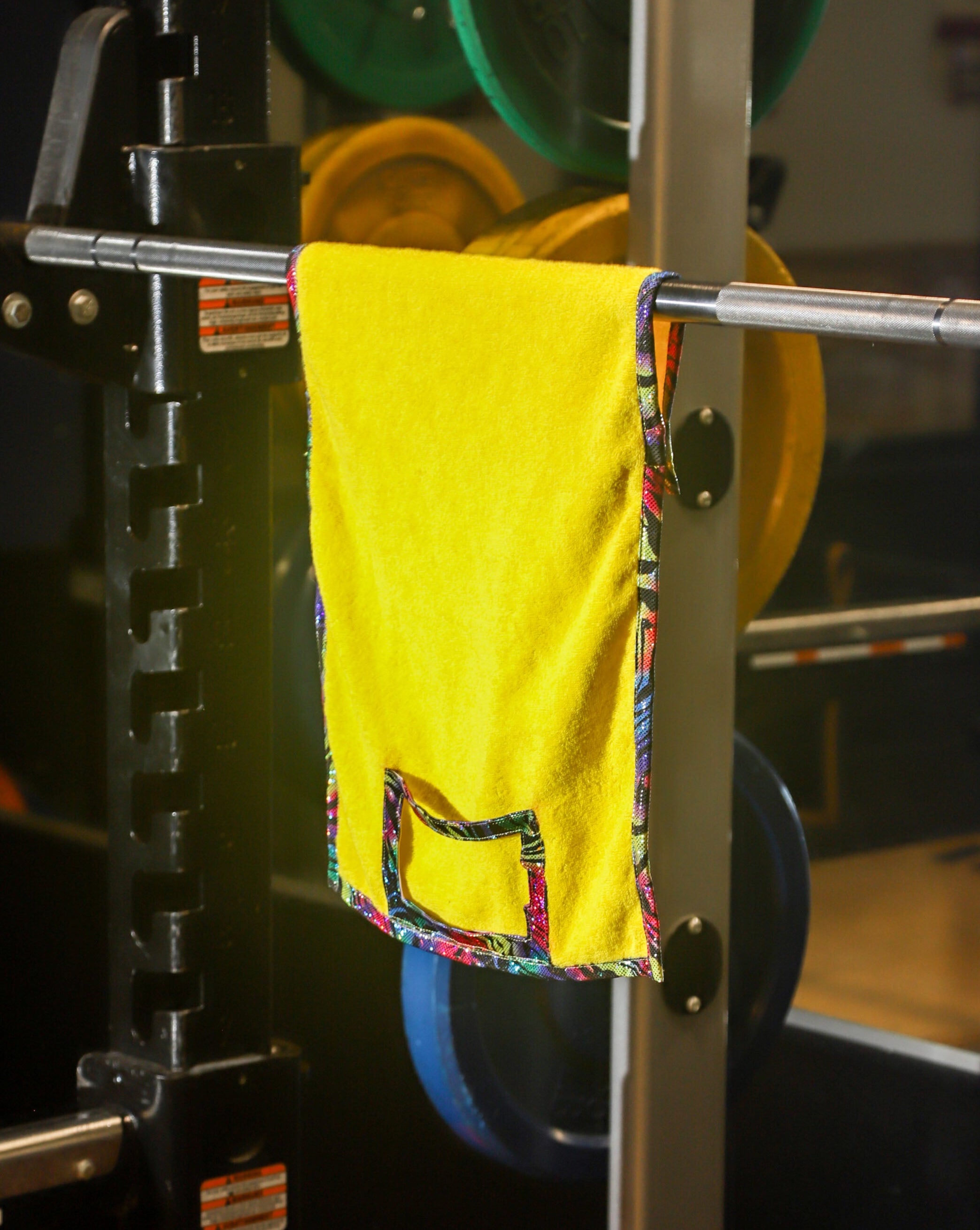 Yellow towel hanging on a weight rack with weight plates in the background