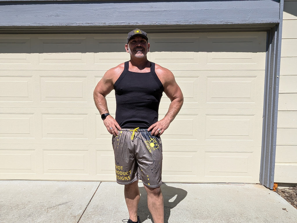 Big Mike wearing the Pivot Performance Shorts — charcoal black four-way stretch with yellow splatter print, front view