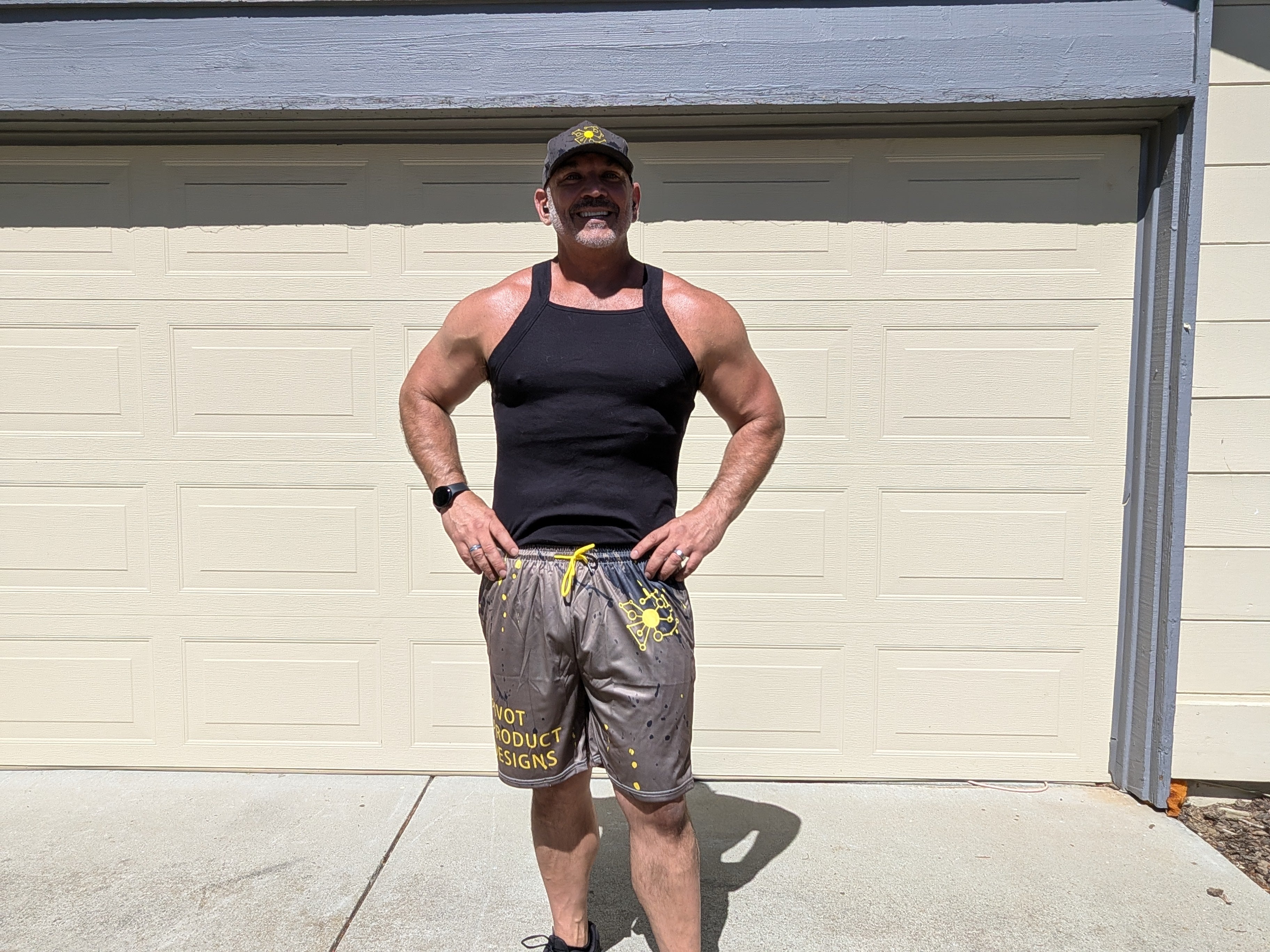 Big Mike wearing the Pivot Performance Shorts — charcoal black four-way stretch with yellow splatter print, front view