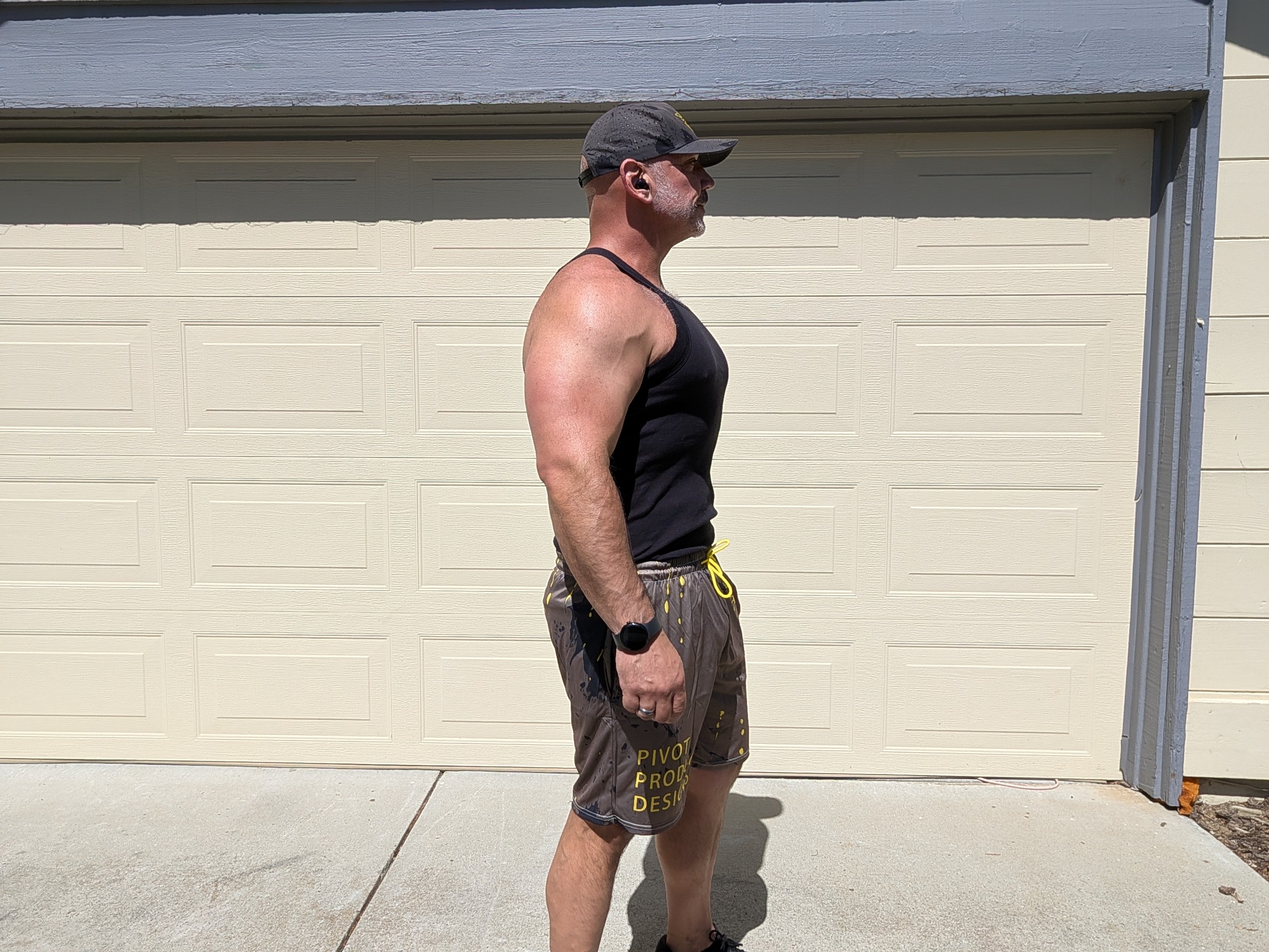 Side view of the Pivot Performance Shorts on Big Mike — yellow PIVOT PRODUCT DESIGNS leg wordmark visible on charcoal fabric